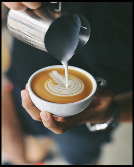 Ein Poster von einem Barista, der kunstvoll Milch in eine Tasse Kaffee gießt und ein Muster kreiert.