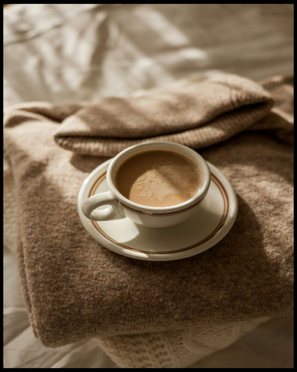 Ein Poster von einer Tasse Kaffee auf einem gemütlichen, beigen Pullover.